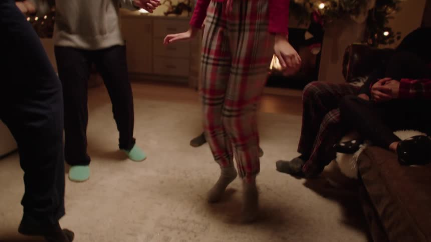 People dancing in the living room near the christmas tree