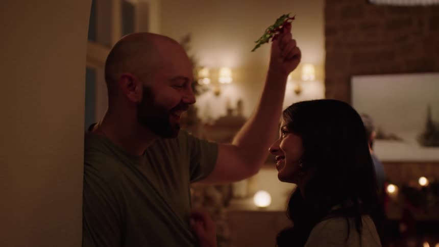 Young couple celebrating christmas kiss under the mistletoe