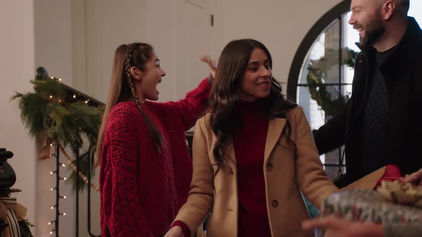 Family carrying christmas presents greet each other with hugs