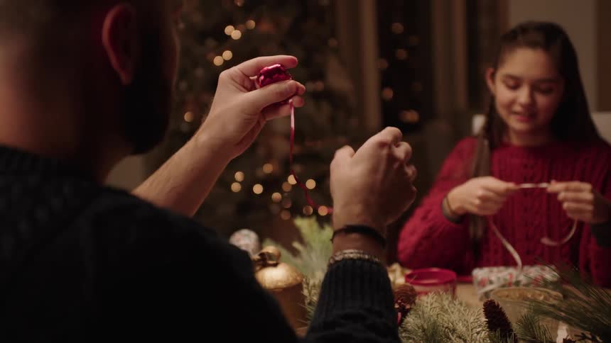 Family sitting at the table at night using a gift ribbon