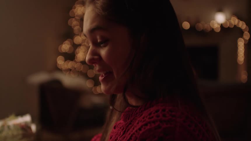 Lady smiling while holding a wrapped gift indoor at night