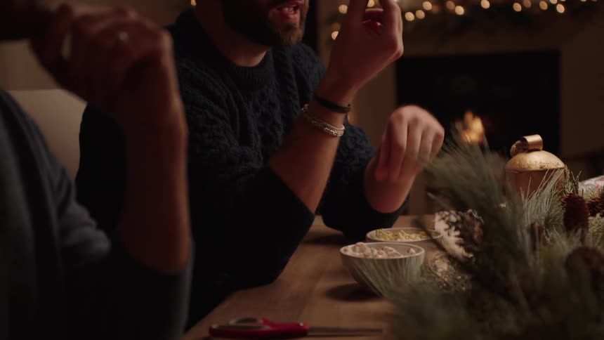 A bald bearded man gestures while telling a story at the table
