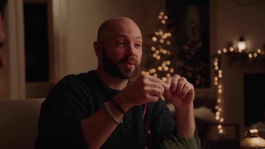 Portrait of a man talking while sitting at the table while holding a gift ribbon
