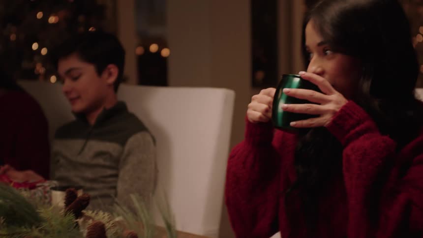 A woman drinks out of a cup while sitting with others at a table