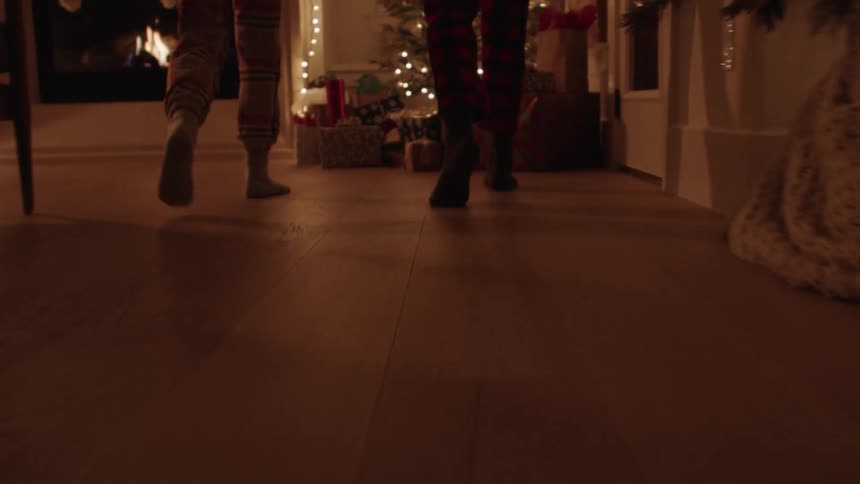 Siblings running to open the presents under the christmas tree