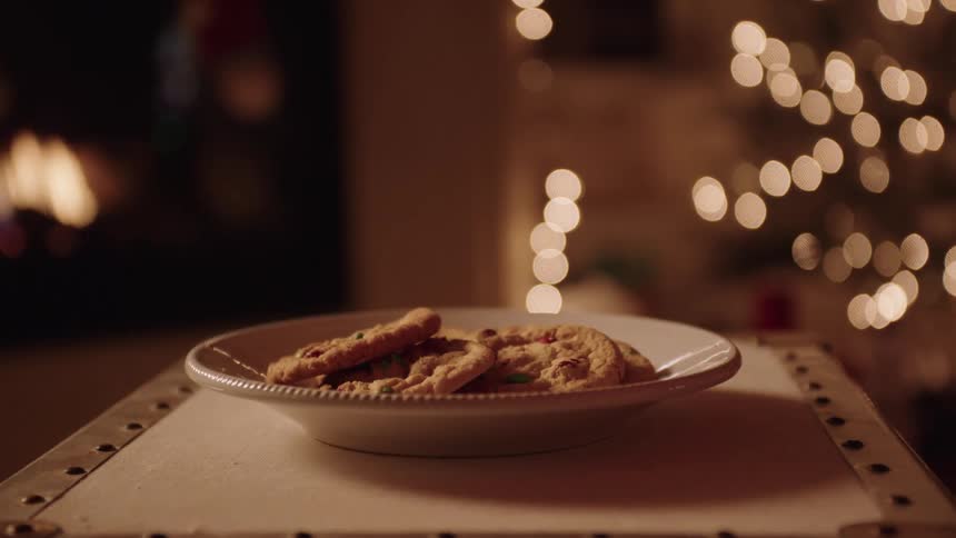 Person placed a plate of cookies and a bottle of milk on a surface at night