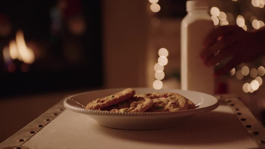 A person leaving a plate of cookies and a bottle of milk on christmas night