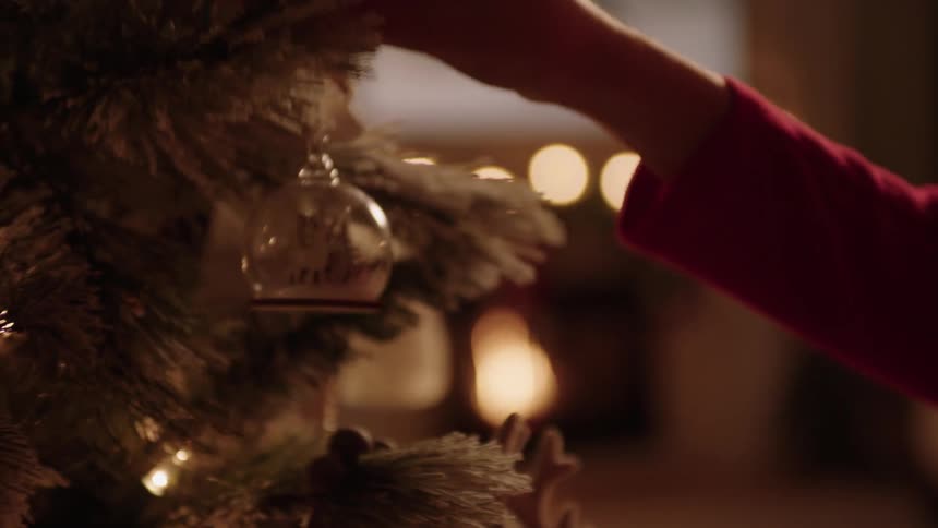 A person hanging an ornament on a christmas tree