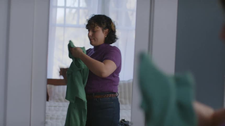 Woman trying clothes in front of the bedroom mirror