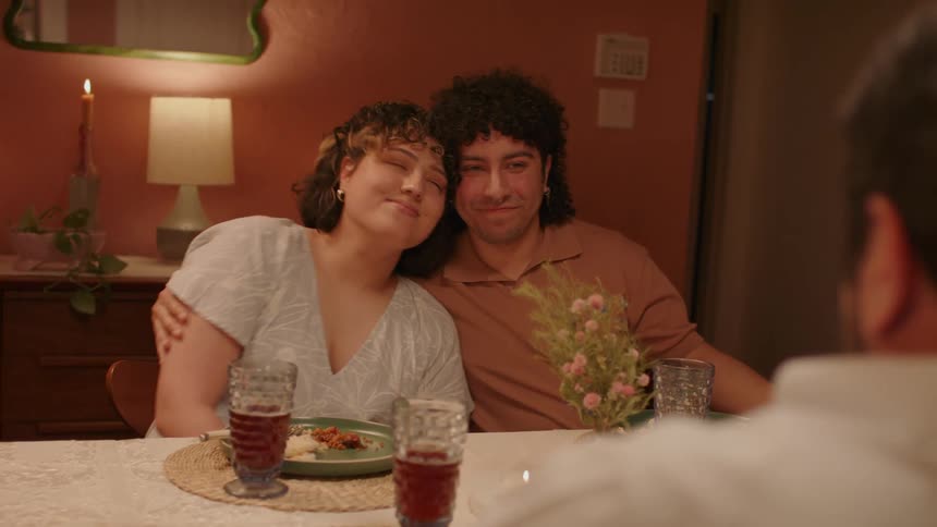 Man and woman seated at the dining table smiling and hugging each other