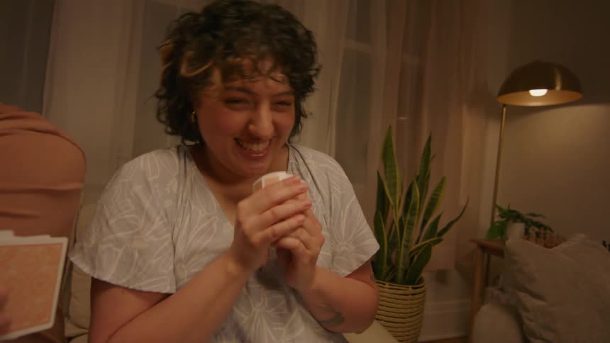 Woman hands card to a friend during a card game at night