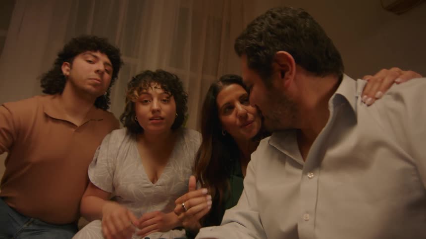 Family and friends pose to take a picture of themselves in the living room at night
