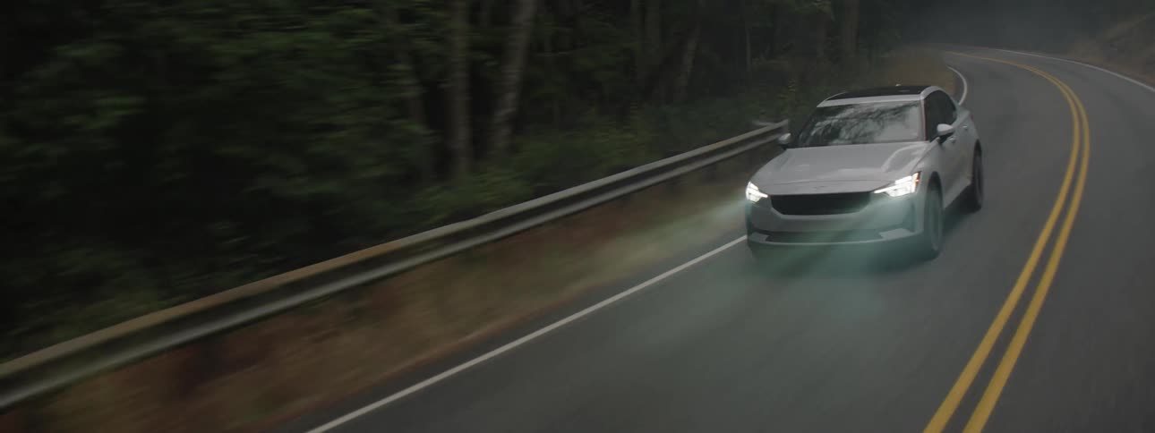 White car driving on highway through a forest