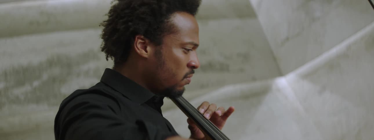 A man playing cello while seated indoor