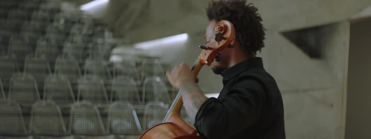 A man playing cello on stage but the audience is empty