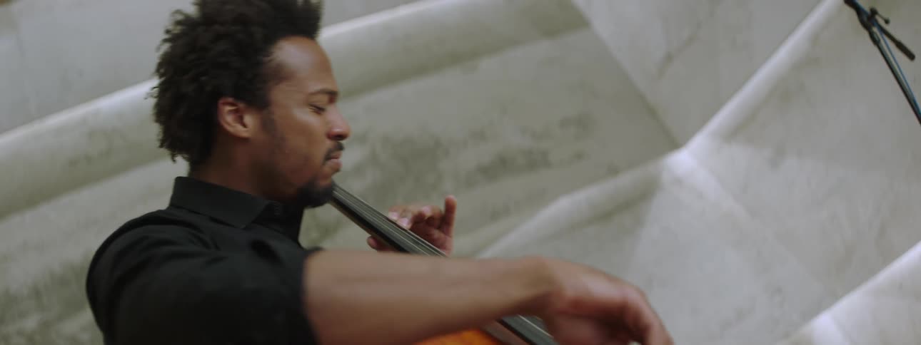 A man playing a cello while seated indoor
