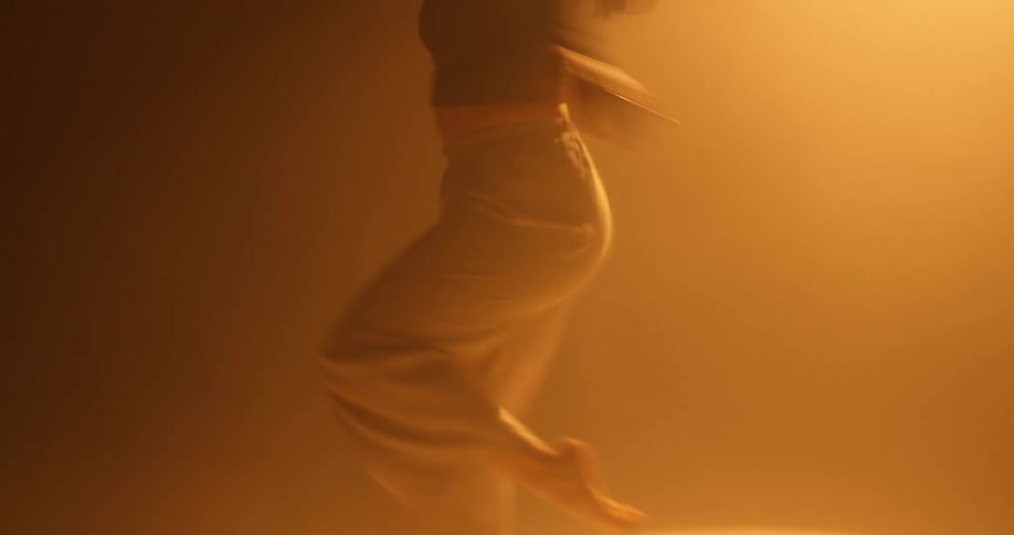 Young woman energetically dancing under a yellow spotlight