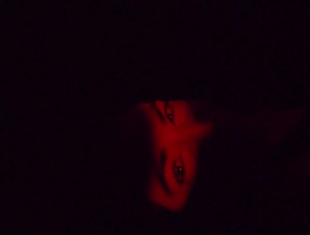 A womans eyes illuminated by a red light in a dark environment