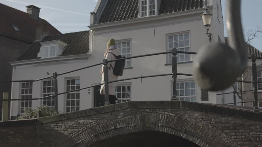 Woman crossing a small bridge in a residential neighborhood