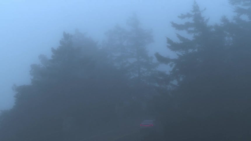 A electric vehicle driving over a foggy bridge at dawn