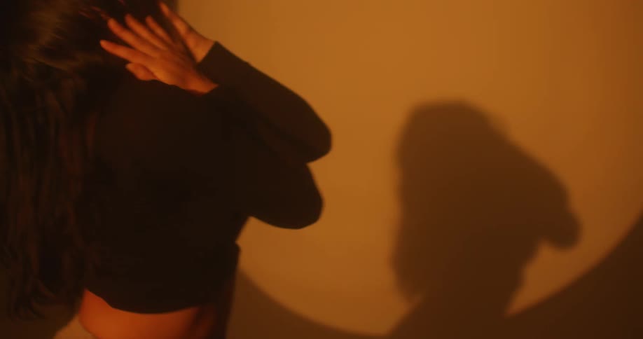 Young woman wearing a black sweater dance in front of a spotlight