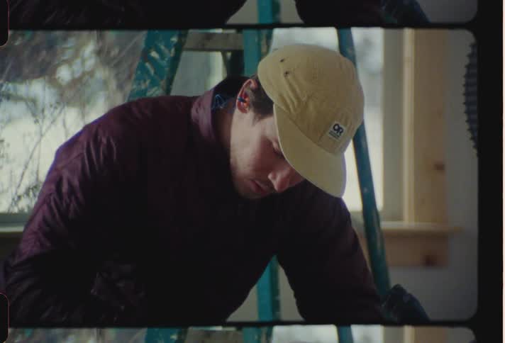 A man on face cap working on something indoor at midday