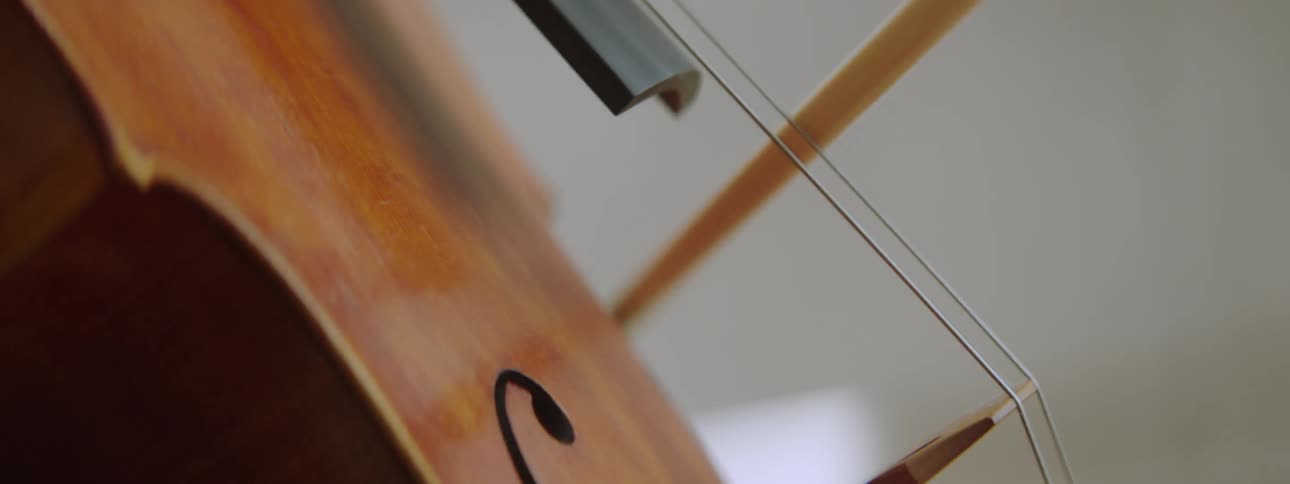 A human hand holding a piece of a violin and scraping it against the strings of the violin to make sound