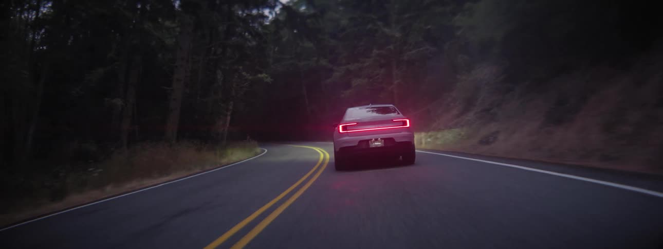 A Polestar Electric Vehicle travels on a road through the forest