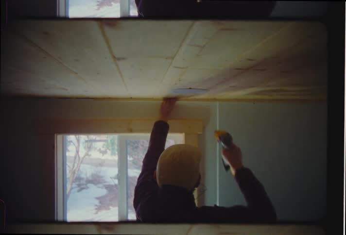 Man fixes the ceiling indoor with a tool during the day