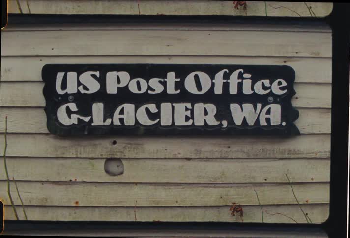 A post office sign is on the side of the building