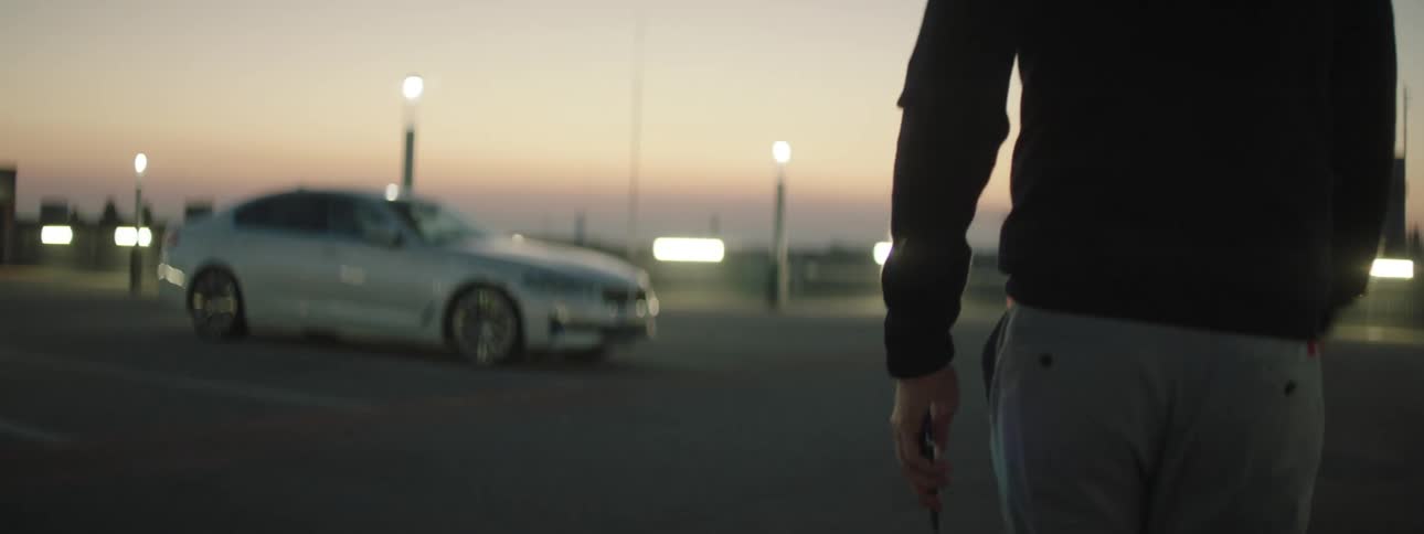 A person walking towards their car while using their cell phone