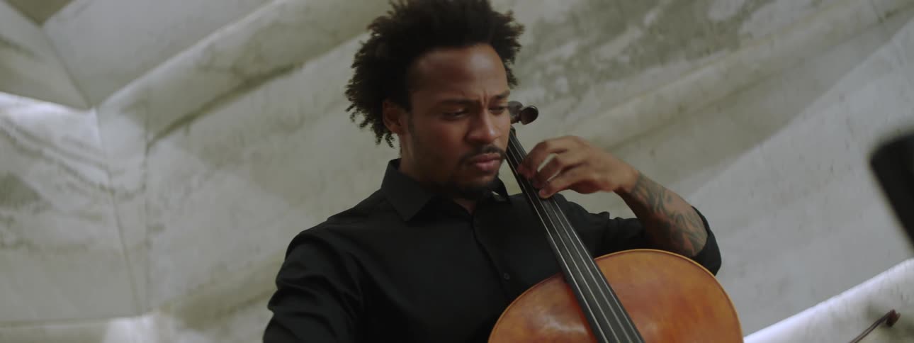 An inspired musician plays the cello in front of a microphone