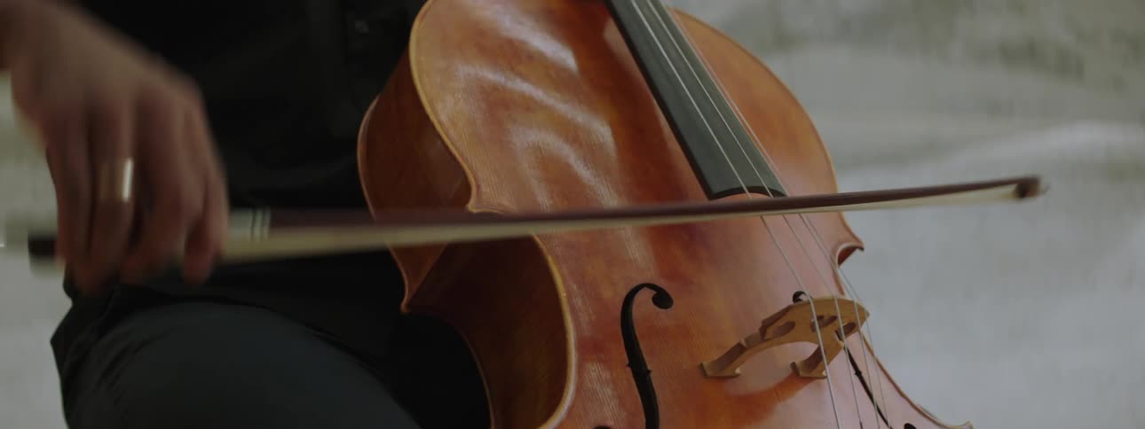 A man playing cello while seated indoor