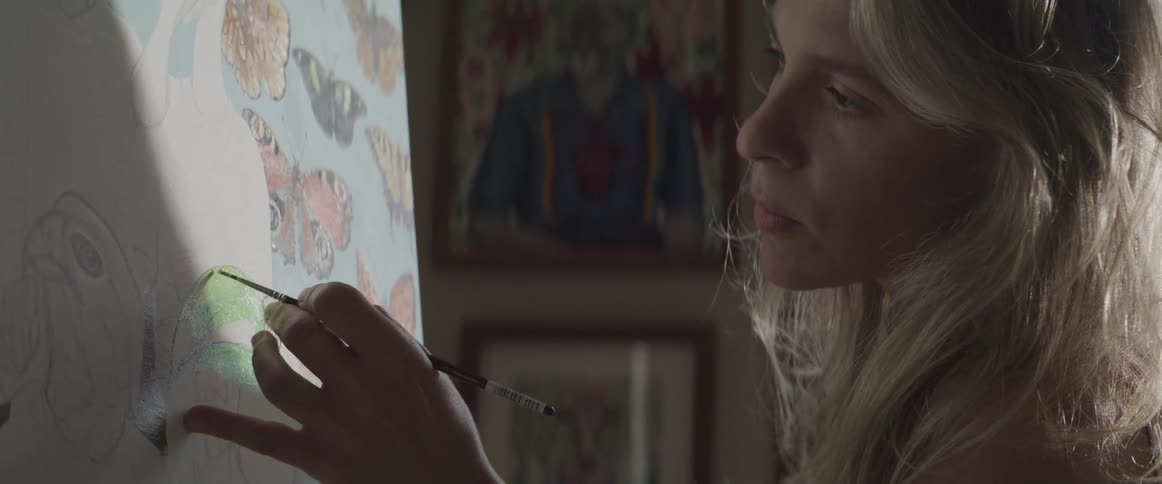 A woman painting on a canvas located on a wall