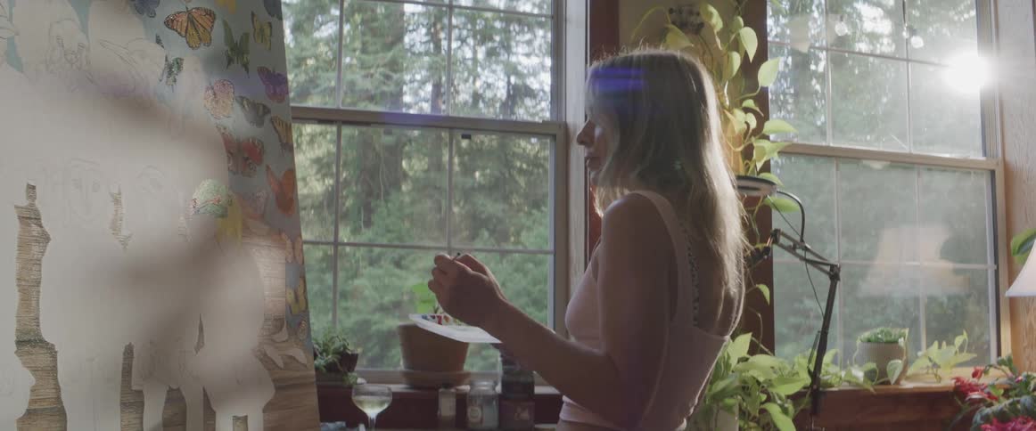 Blonde woman paints on canvas indoors near window