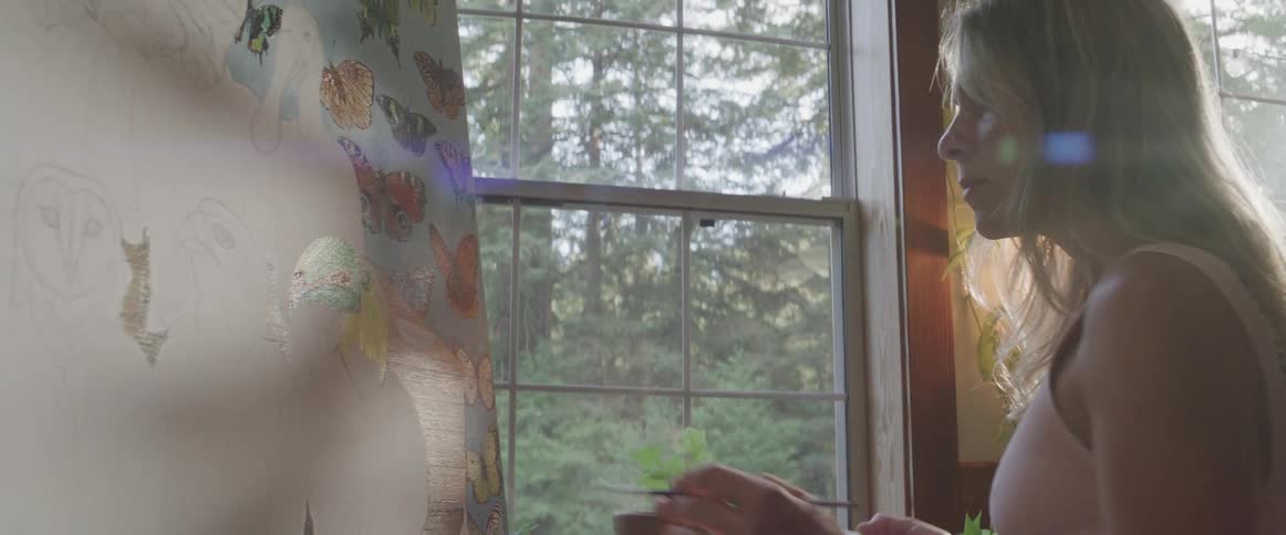 A woman is painting a colorful mural of various animals near a window