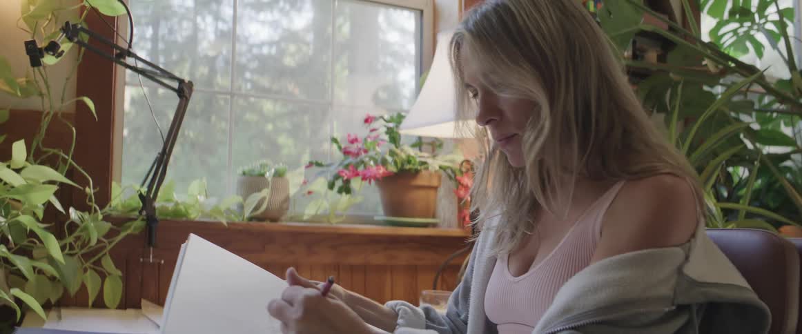 Woman sitting on a chair in a room drawing in a notebook