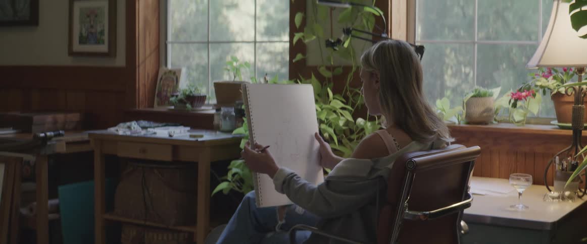 Woman sitting in a room drawing in a notebook
