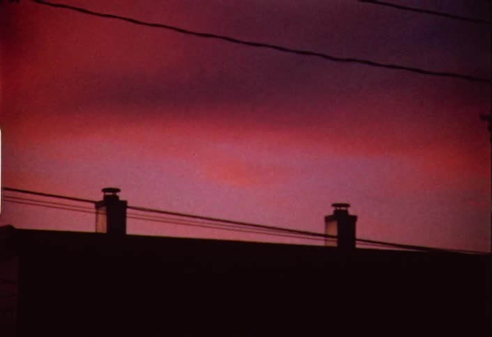 The sky is red as the sun sets above a building