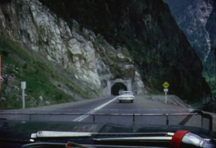 Vehicles traveling toward a road and into a mountain tunnel
