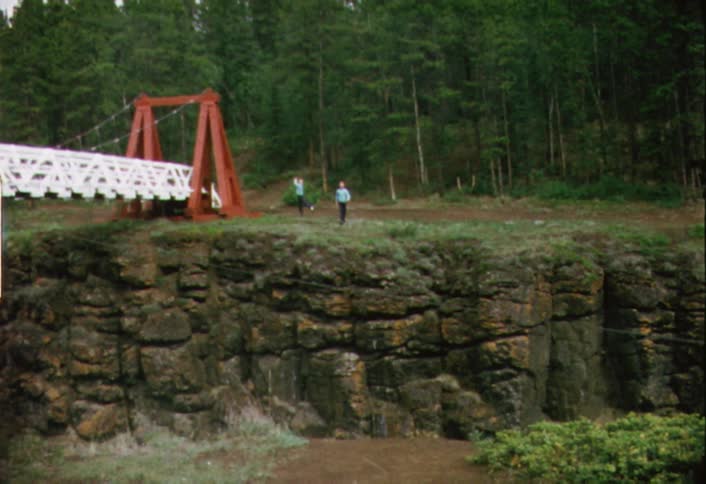 Two young people waving at the camera from across a crevice