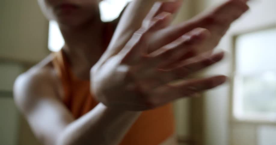 A woman twists and contorts her hands as if performing a dance