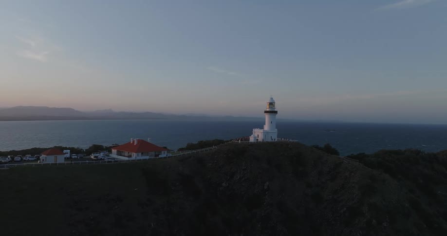 White lighthouse on a coastal cliff overlooking the ocean at dusk