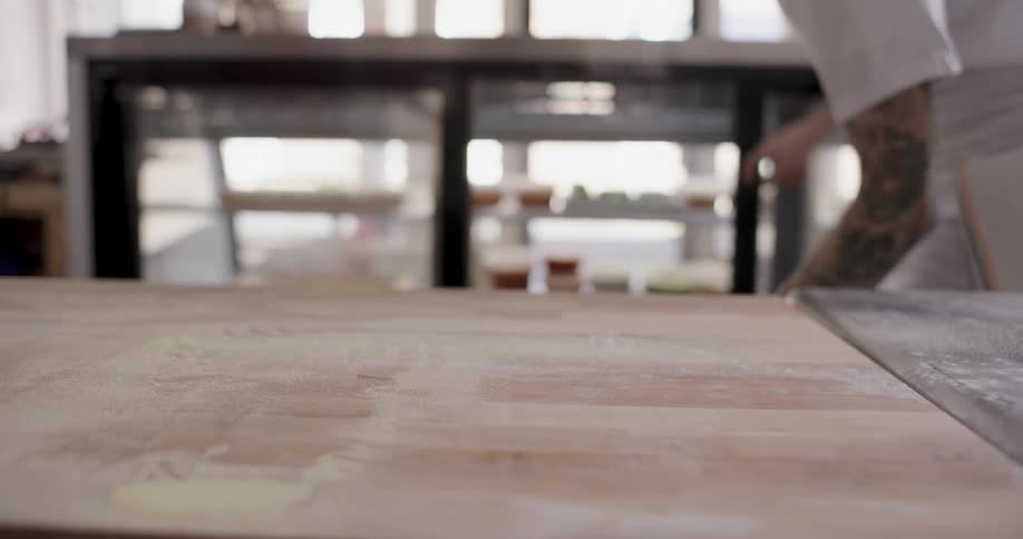 A man places a tray containing uncooked pasta into a display case