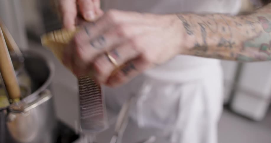 A person grates cheese while preparing a meal