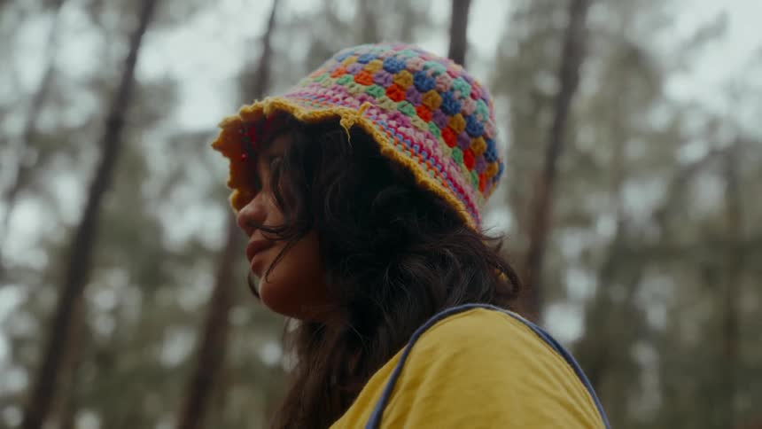 Closeup profile shot of a young Asian woman in a forest wearing a quirky knit hat