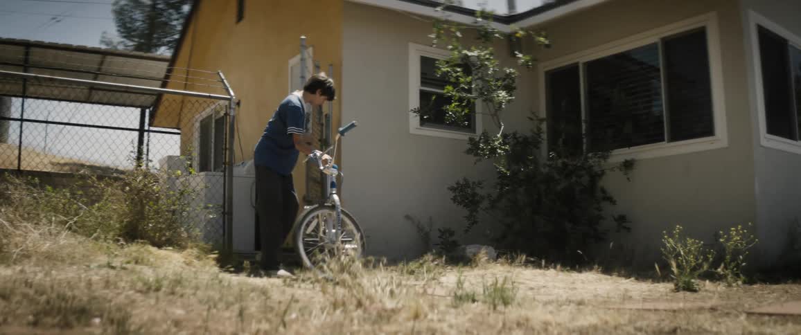 A clip of a boy pushing a bicycle