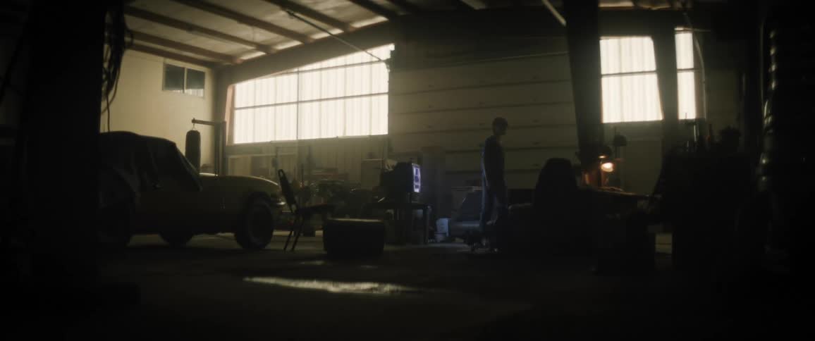A teenager alone in a closed garage sits on a couch and watches tv