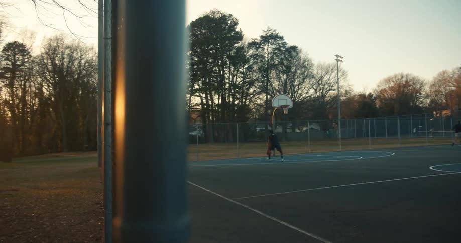 Man on a public court shooting a basketball on friday