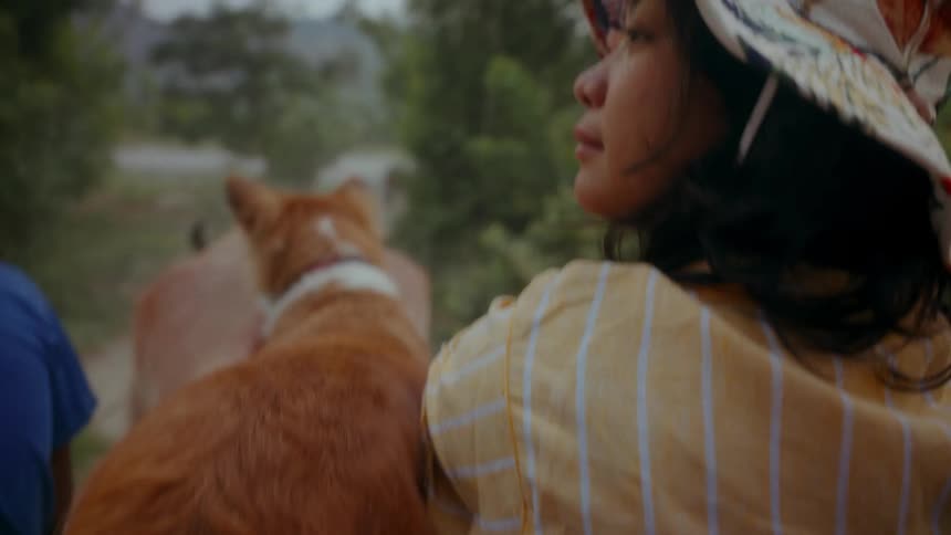 A young Asian woman rides on a carriage through the Philippines with her dog